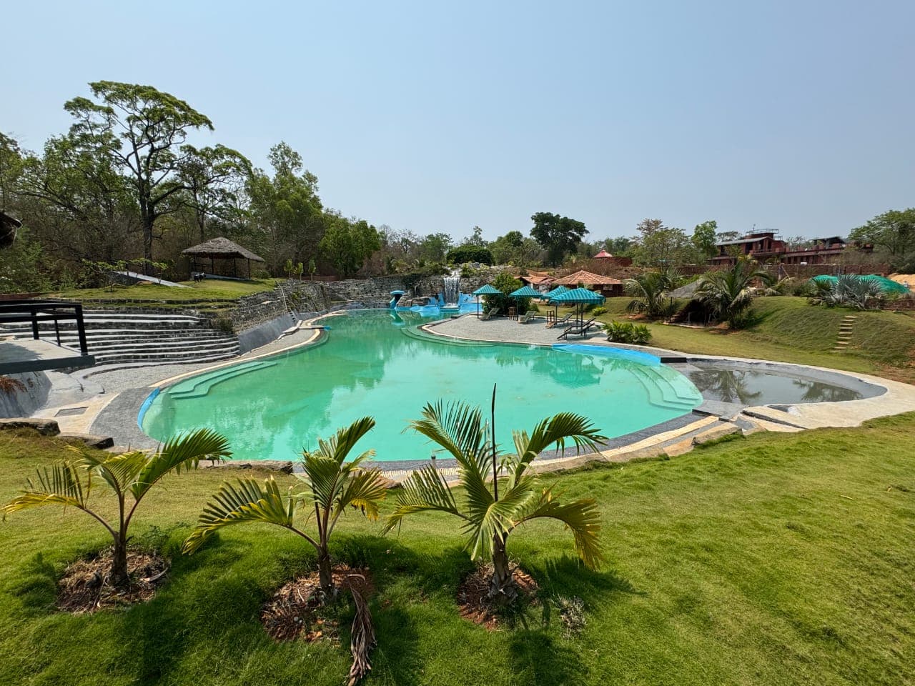 Resort swimming pool with palm trees and water slide